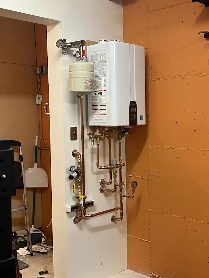 Plumbing technician inspecting water heater connections in West Hempfield